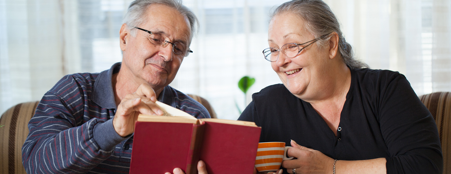 Couple smiling as they read together with a cup of coffee