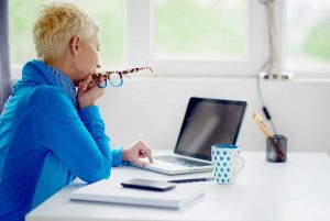 Woman in front of computer holding glasses